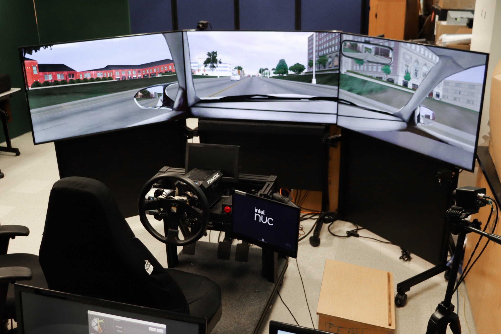 The complete BAT Lab driving simulator with a curved multi-monitor display, steering wheel, driver seat, computer, and camera equipment.
